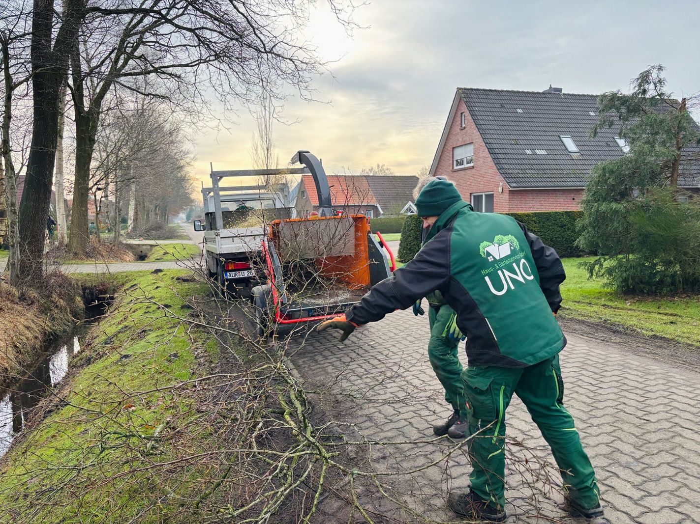 Zwei Mitarbeiter zerhäckseln einen Baum