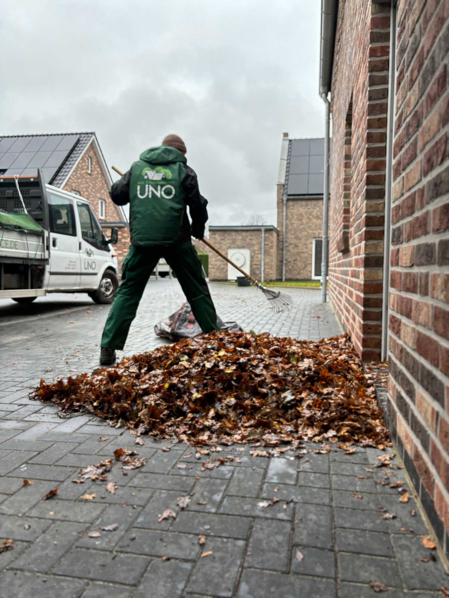 Ein Mitarbeiter fegt Laub zusammen