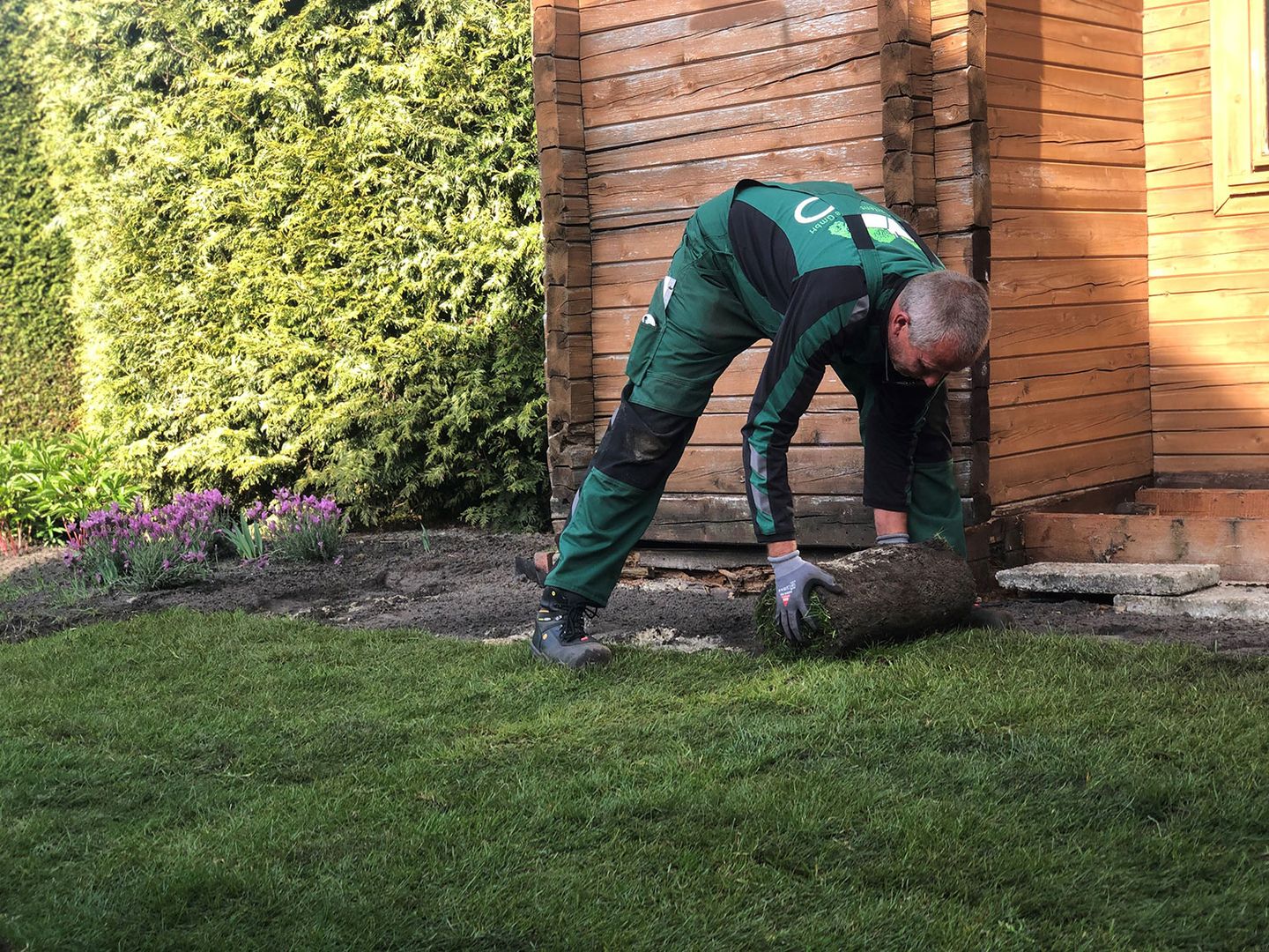 Ein Mitarbeiter rollt einen Rasen aus